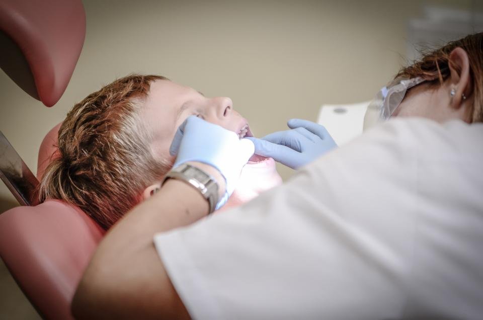 A hygienist cleaning a patients teeth in the chair