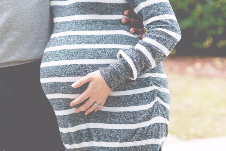 An expectant mother resting a hand on her bump