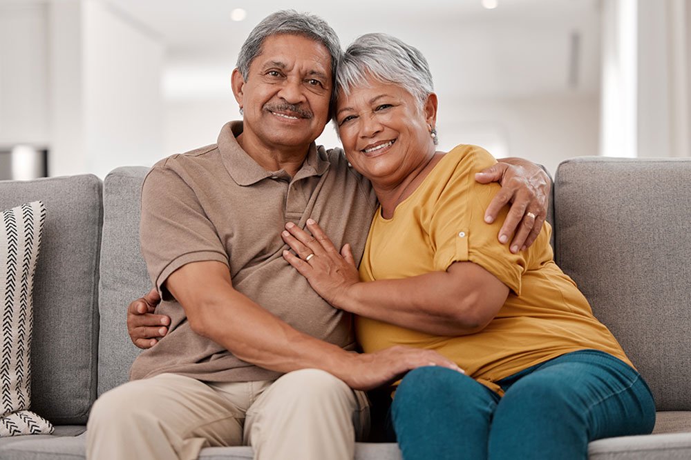 A senior couple smiling together on their sofa
